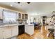 Open kitchen featuring light cabinetry, stone backsplash, modern appliances, and wooden floors leading to the dining area at 1603 Drowning Creek Rd, Dacula, GA 30019