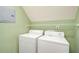 Compact laundry room with white washer and dryer units, a shelf, and green walls at 1603 Drowning Creek Rd, Dacula, GA 30019