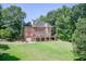 Two-story brick home with a walk-out basement and spacious deck, set against a backdrop of lush greenery at 1603 Drowning Creek Rd, Dacula, GA 30019
