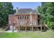 Expansive brick home featuring a large deck, walk-out basement, and lush green lawn surrounded by mature trees at 1603 Drowning Creek Rd, Dacula, GA 30019