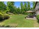 Lush backyard featuring a manicured lawn, mature trees, and inviting patio area with dining set at 2196 Abbott Dr, Buford, GA 30519