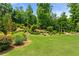 Beautifully landscaped backyard with mature trees, manicured shrubs, and a charming arbor feature at 2196 Abbott Dr, Buford, GA 30519