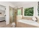 Bright main bathroom featuring a glass shower, soaking tub and views of the outdoors at 2196 Abbott Dr, Buford, GA 30519