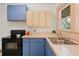 Well-lit kitchen features blue cabinets, modern appliances, and a stainless steel sink with a view of the outdoors at 2791 Pearl St, East Point, GA 30344