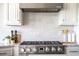 Modern gas range stove with stainless steel vent hood and neutral backsplash at 714 Billings Farm Ln, Canton, GA 30115
