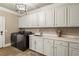 Bright laundry room with marble countertops, white cabinets, and modern appliances at 714 Billings Farm Ln, Canton, GA 30115