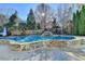 Beautiful in-ground pool surrounded by lush landscaping and a stone retaining wall at 3350 Vista Creek Dr, Dacula, GA 30019