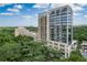 Exterior of high-rise building with many windows surrounded by lush green trees against a bright blue sky at 2233 Peachtree Ne Rd # 1202, Atlanta, GA 30309