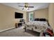 Cozy bedroom with a ceiling fan, TV, and a comfortable bed with patterned bedding, a window looking out to the yard at 48 Scenic Ovlk, Acworth, GA 30101