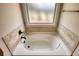 Soaking tub with tile surround beneath frosted window for natural light at 200 Baumgard Way, Locust Grove, GA 30248