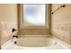 Close-up of a bathtub surrounded by decorative tile and a frosted window at 200 Baumgard Way, Locust Grove, GA 30248
