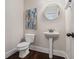 Charming half bath with pedestal sink, round mirror, and wood-look flooring at 5288 Clingman Ct, Douglasville, GA 30135