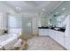 A bright bathroom featuring a soaking tub, a glass block shower, and a large vanity with black countertop at 1617 Windsor Ne Pkwy, Brookhaven, GA 30319