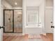 Elegant bathroom featuring a glass shower, soaking tub, and wood floors perfect for relaxation at 1312 Mcgarity Rd, Temple, GA 30179