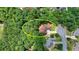 Aerial view of a red brick house surrounded by lush greenery and mature trees in a quiet, residential neighborhood at 4580 Lakefield Bend Bnd, Berkeley Lake, GA 30096