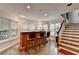A bar with seating and windows, next to stairs with natural wood at 4580 Lakefield Bend Bnd, Berkeley Lake, GA 30096