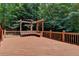 Expansive wood deck features a built-in bench and pergola, creating an inviting outdoor space surrounded by trees at 4580 Lakefield Bend Bnd, Berkeley Lake, GA 30096