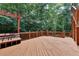 Spacious wooden deck with built-in seating and pergola overlooks a lush wooded backyard, perfect for outdoor relaxation at 4580 Lakefield Bend Bnd, Berkeley Lake, GA 30096