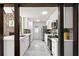 Kitchen with white cabinets and stainless steel appliances seen through a dark wood trimmed entry at 1364 Tsali Trl, Morrow, GA 30260