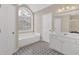 Bathroom showcasing a soaking tub, arched window, and decorative tile floor at 1715 Branchwood Ct, Powder Springs, GA 30127