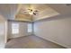 Spacious carpeted bedroom with a tray ceiling, ceiling fan, and lots of natural light from dual windows at 1345 Smoke Hill Dr, Hoschton, GA 30548