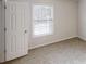 Cozy bedroom features neutral carpet, natural light from the window, and a white door at 1345 Smoke Hill Dr, Hoschton, GA 30548