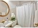 Bright bathroom featuring a circular mirror, a sink, toilet with decor, and white shower curtain at 5712 Overlook Cir, Powder Springs, GA 30127