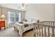 Bright bedroom featuring a ceiling fan, window with curtains, bed and crib at 5712 Overlook Cir, Powder Springs, GA 30127