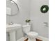 Well-lit powder room featuring a pedestal sink, round mirror, and decorative wreath at 1583 Mosaic Way, Smyrna, GA 30080