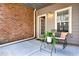 Charming porch area with cozy seating, featuring a brick wall, grey siding, and a potted plant at 1583 Mosaic Way, Smyrna, GA 30080