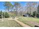 Spacious backyard with a decorative stone pathway, shed, mature trees, and well-maintained lawn at 477 Glouchester Dr, Locust Grove, GA 30248