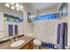 Well-lit bathroom featuring a sink vanity, toilet, shower with a blue and white checkered curtain, and stylish decor at 477 Glouchester Dr, Locust Grove, GA 30248