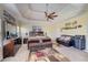 A primary bedroom showcasing a tray ceiling, ceiling fan, and a seating area with a loveseat at 477 Glouchester Dr, Locust Grove, GA 30248