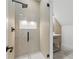 Modern shower with glass door, neutral stone tiling, and black hardware at 1857 Defoor Ave, Atlanta, GA 30318