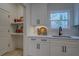 Bright auxiliary counter with white cabinetry, black pulls, open shelving, and decorative accents at 220 Nicklaus Cir, Social Circle, GA 30025