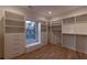 A well-lit walk-in closet with wooden floors, custom shelving, and a window with bench seating at 581 Sherwood Ne Rd, Atlanta, GA 30324