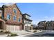 View of the townhome exteriors displaying the stone facade, arched entry, and manicured lawn at 202 Via Lucca, Woodstock, GA 30188