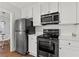 Modern kitchen with stainless steel appliances, white cabinetry, and subway tile backsplash at 1600 Temple Ave, Atlanta, GA 30337