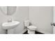 A clean powder room features a pedestal sink, toilet, and a sleek round mirror at 1891 Audubon Park Ln, Decatur, GA 30033