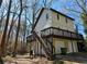 Home's rear exterior with deck, stairs, and lower-level garage access nestled among trees at 1920 Moores Mill Nw Rd, Atlanta, GA 30318