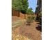 A fenced backyard features gravel and stone landscaping elements and manicured bushes and pine straw at 2021 Towneship Trl, Roswell, GA 30075