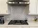 Close-up of the kitchen range featuring modern Monogram range hood and subway tile backsplash at 2021 Towneship Trl, Roswell, GA 30075