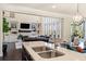 Open-concept kitchen with stainless steel appliances overlooking a living room with large windows and built-in shelving at 2820 Garonne Way, Cumming, GA 30041