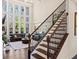 Modern staircase with dark hardwood steps, black railings, and large windows bringing natural light to the living room at 2820 Garonne Way, Cumming, GA 30041
