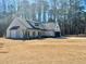 Side view of new home with a large yard, covered entry, and a two-car garage set on a wooded lot at 34 Harmony Ridge Dr, Temple, GA 30179
