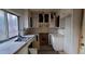 A U-shaped kitchen featuring white cabinets and countertops beneath a window and with dated finishes at 868 Maxey Hill Ct, Stone Mountain, GA 30083