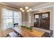 Cozy dining area featuring a wooden table, stylish chandelier, and natural light from a large window at 4152 Woodward Mill Rd, Sugar Hill, GA 30518