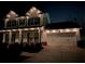 Exterior view of a two-story home with white siding and a white garage door illuminated at night at 4152 Woodward Mill Rd, Sugar Hill, GA 30518