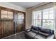 Office space with hardwood floors, a comfortable black leather couch, and barn doors, providing style and function at 4152 Woodward Mill Rd, Sugar Hill, GA 30518