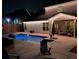 Backyard pool and patio illuminated at night, with stone fire pit and chairs at 4152 Woodward Mill Rd, Sugar Hill, GA 30518